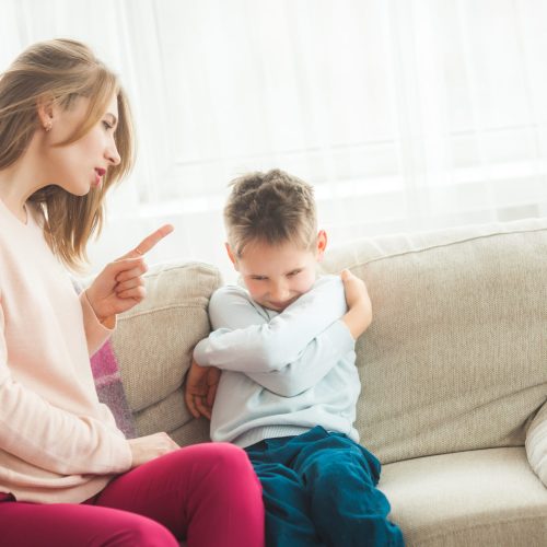 Mother punishing her little son at home. Mom scolds her child