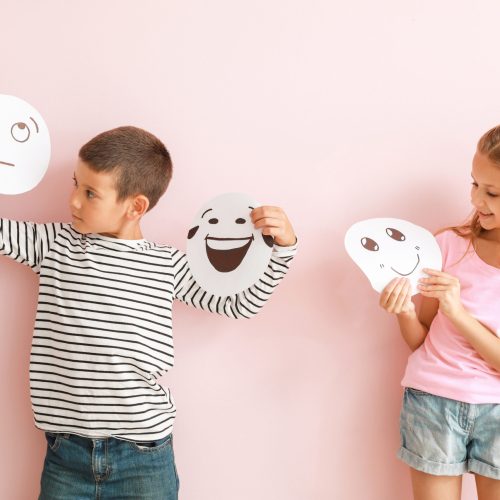 Little children with drawn emoticons on color background