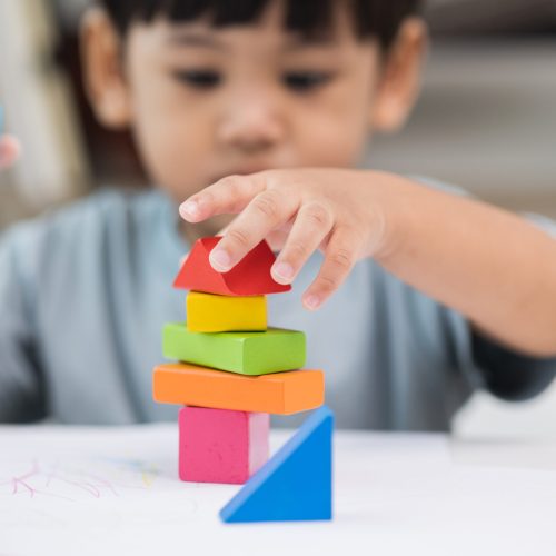 Close up Children hand Practice the skills of playing with wooden toys on the table in living room. Asian little boy education from home. Developing children's learning before entering kindergarten